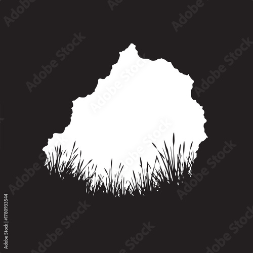 Black silhouette of cave entrance with grass foreground