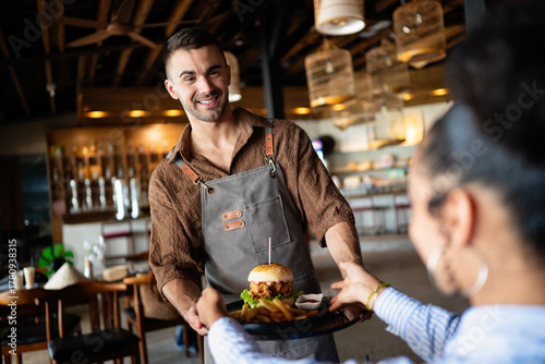 Tableau sur toile Casual dining lifestyle, waiter serves a delicious burger and fries in a relaxed