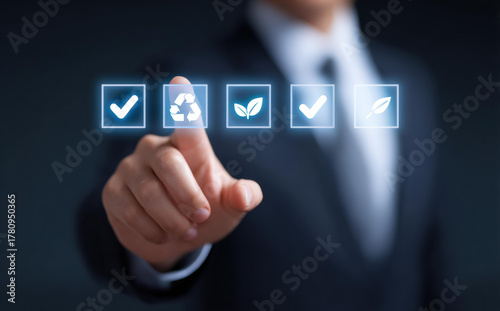Focused businessman pointing at virtual screen with green environment icons. man selects recycling symbol for sustainability and ESG compliance on futuristic interface