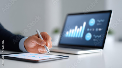 Focused businessman doing financial analysis with data on chart. Using laptop and tablet with stylus for market research, strategy, and investment growth