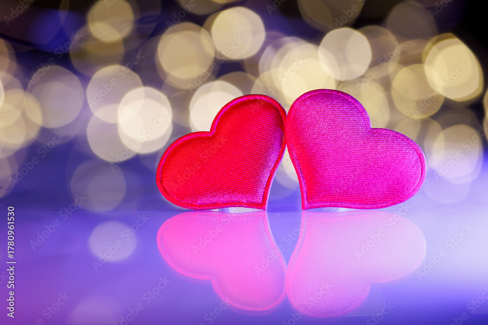 Fototapeta premium Two red hearts with golden bokeh lights. Romantic holiday background for Valentine’s Day, anniversary, wedding, or New Year greeting cards. Symbol of love, joy, and celebration.