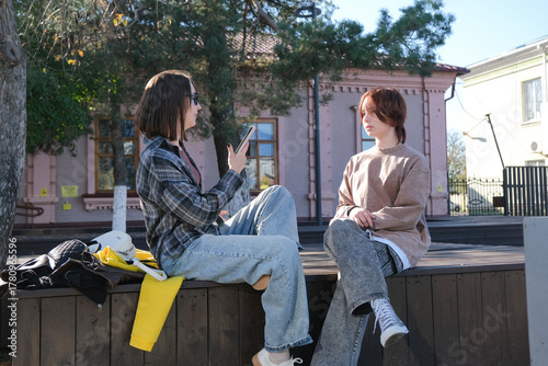 girl and mother sitting on a park bench using mobile phone