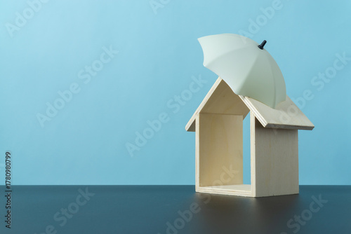 Umbrella toy and mini wooden home show the insurance cover concept
