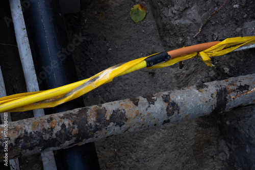 Construction site showing yellow safety tape around exposed utility lines and pipes during maintenance work