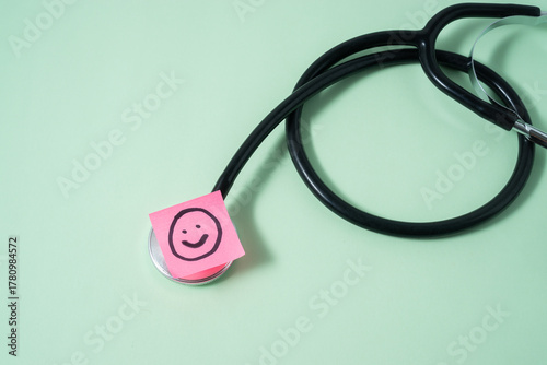 A stethoscope on light green background with a smile emoji