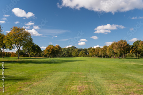 Golf fairway with autumn trees under clear blue sky
