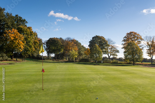 Golf ball near hole on putting green with flagstick