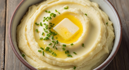 Fototapeta Naklejka Na Ścianę i Meble -  Creamy Mashed Potatoes with Melting Butter and Fresh Chives in a Rustic Bowl.