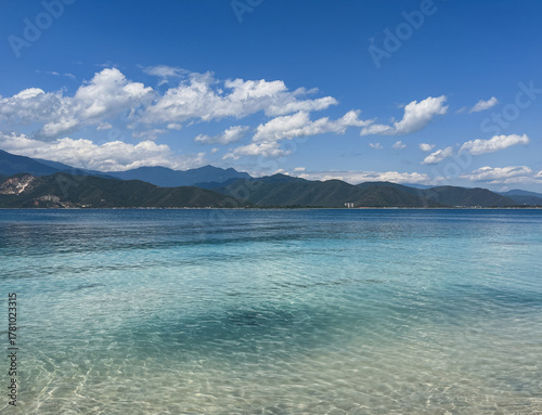 Crystal clear waters of a tropical ocean ( Isla Larga, Venezuela ) with sandy bottom and coastal mountains in the distance - An idyllic summer seascape under a blue sky and white clouds