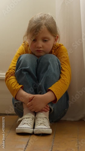 Sad emotional melancholy Caucasian little girl child kid daughter hugging knees sitting on floor thinking trouble family divorce suffer boring isolation at home problem violence bullying sorrowful