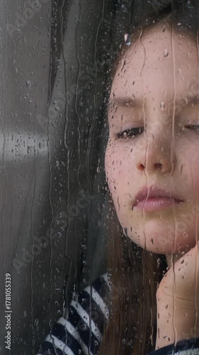Stressed unhappy Caucasian little child kid girl looking out window on rain dropping on glass thoughtful pensive thinking dreaming daughter melancholy worried with family divorce emotion gloomy think
