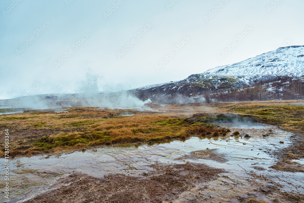 Fototapeta premium Geothermal steam from hot spring with snow mountain on wilderness