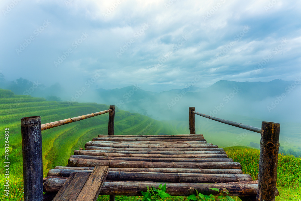 Obraz premium Scenic lush green rice terraces with foggy and bamboo deck on highland in countryside at Ha Giang, Hoang Su Phi, Vietnam