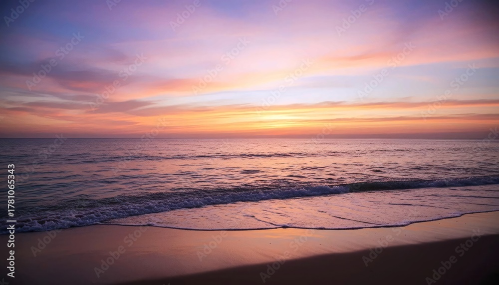 Fototapeta premium Peaceful beach sunset with gentle ocean waves and pastel-colored sky reflecting on wet sand 