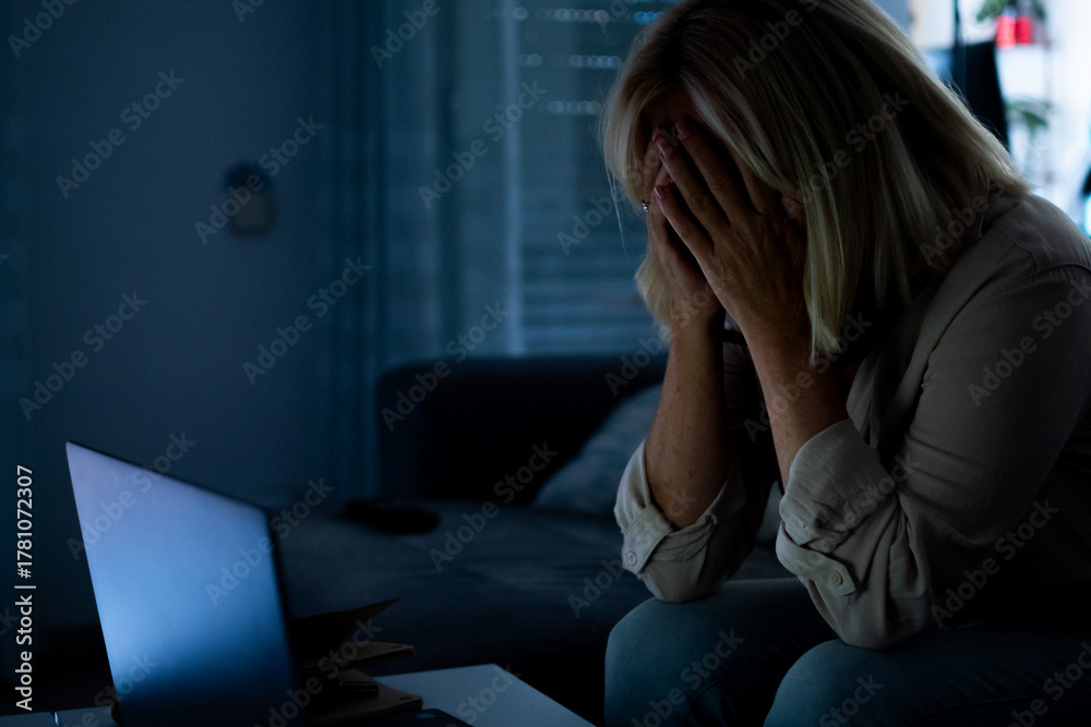 Obraz premium Stressed woman experiencing burnout working on laptop late at night
