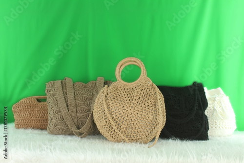 Crocheted bags in different colors and varieties arranged on a white fluffy blanket in front of a green background.