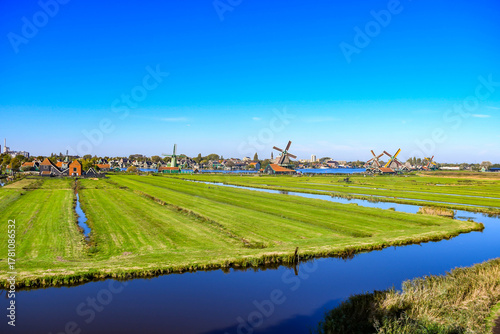 Wide, elevated panoramic view of the vast Dutch countryside with green fields, canals, and windmills on the distant horizon.