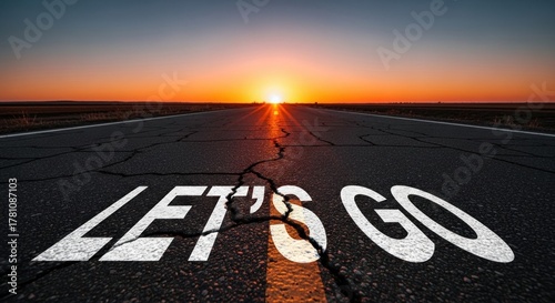 A cracked asphalt road with the words 'Let's Go' painted on it, leading towards a bright, colorful sunset.