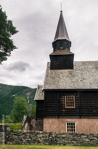 Gjøra Chapel sits in Gjøra village, offering a view of its striking wooden historic building against a backdrop of green mountains and overcast skies, Møre og Romsdal county, Norway