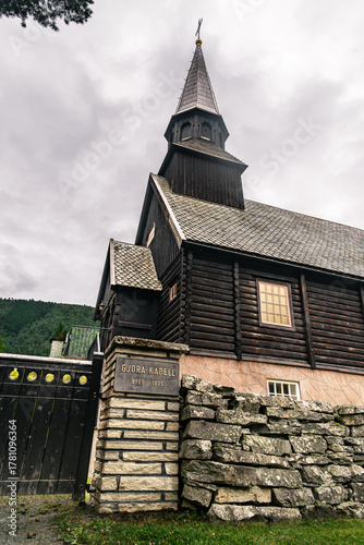 Gjøra Chapel sits in Gjøra village, offering a view of its striking wooden historic building against a backdrop of green mountains and overcast skies, Møre og Romsdal county, Norway