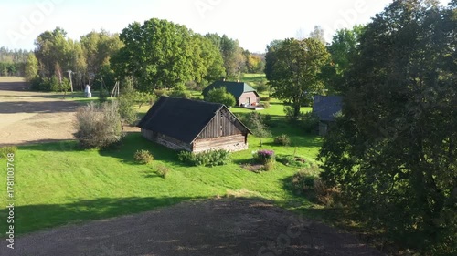 Scenic rural landscape featuring a charming wooden farmhouse surrounded by lush greenery, showcasing gradual camera zoom in on the serene countryside setting