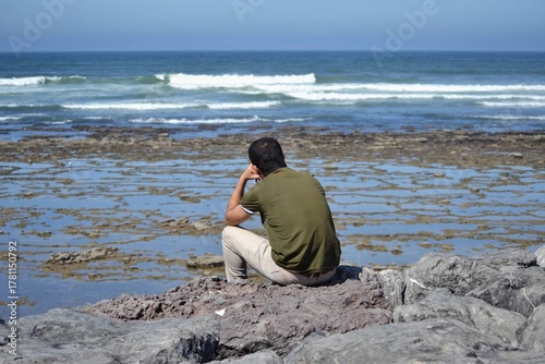 Man Sitting on Rocks looking at the Atlantic Ocean in Casablanca, Morocco
