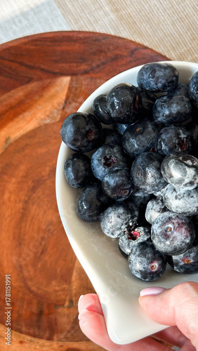 Fresh blueberries in white bowl on wood surface - concept of healthy eating, food bloggers, organic markets