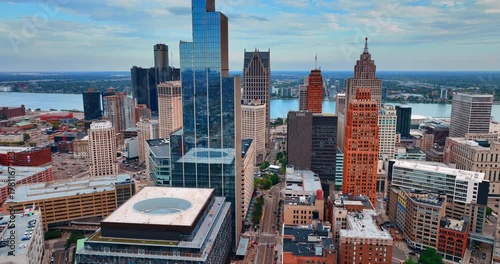 Flying closer to the glass skyscraper in the downtown of Detroit, Michigan, USA. Waterscape of the Detroit River at backdrop.