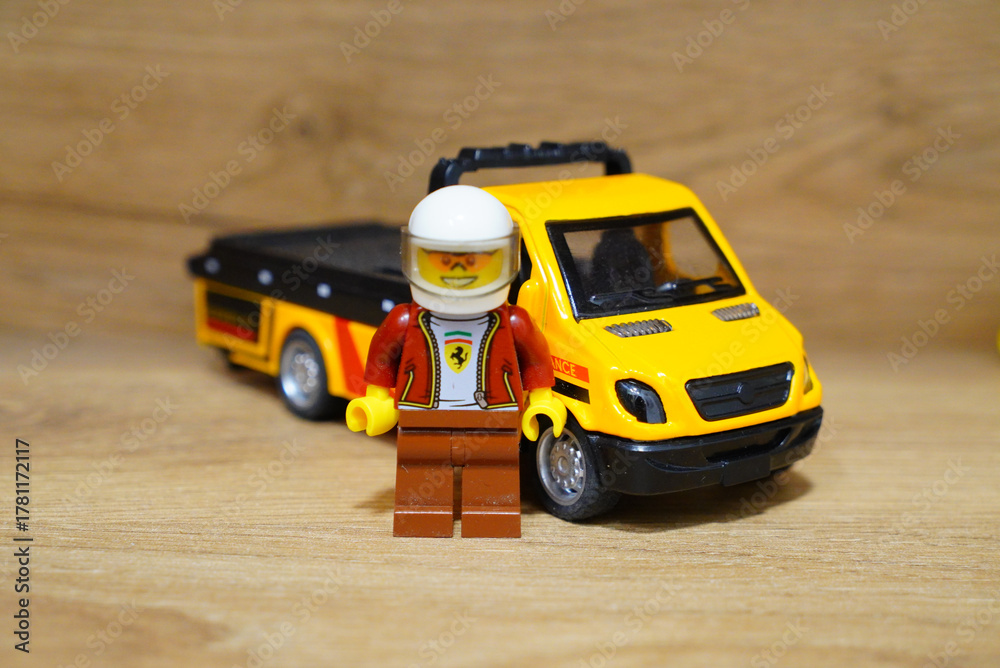 Fototapeta premium Lego minifigure with a yellow tow truck on a wooden surface