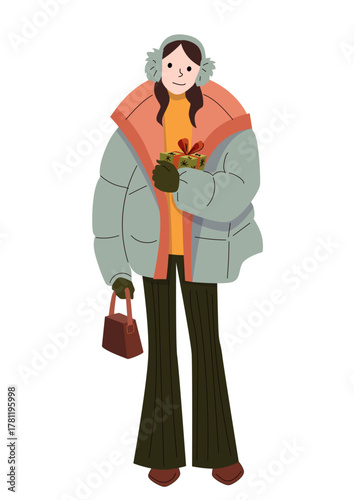 Smiling woman in winter outfit holding holiday gift box and handbag wearing earmuffs puffer jacket gloves and flared pants in cozy seasonal style