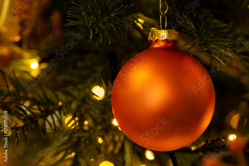 Orange Christmas Bauble Ornament on Evergreen with Warm Lights
