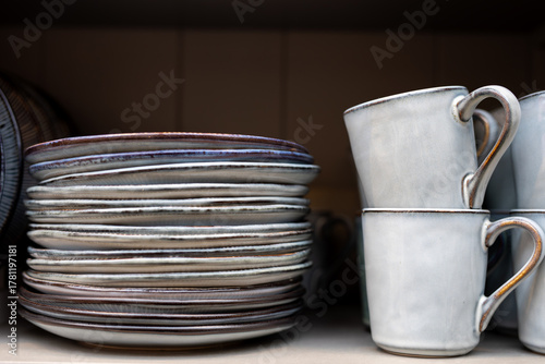 Stack of Ceramic Plates and Mugs on a Shelf