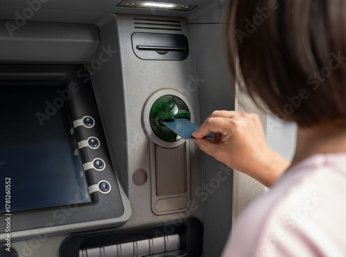 Schilderij op canvas Woman inserts bank card into ATM machine, making cash withdrawal or payment