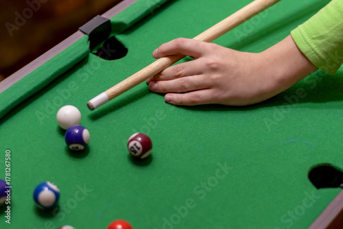 Canvas Print Close-up of teenager's hand holding cue stick while aiming at billiard balls on