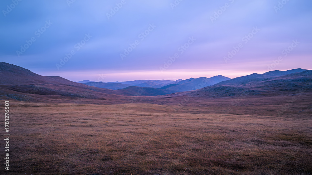 Obraz premium A picturesque landscape featuring a broad plain and far - off mountain ranges bathed in a soft pastel - colored sky.