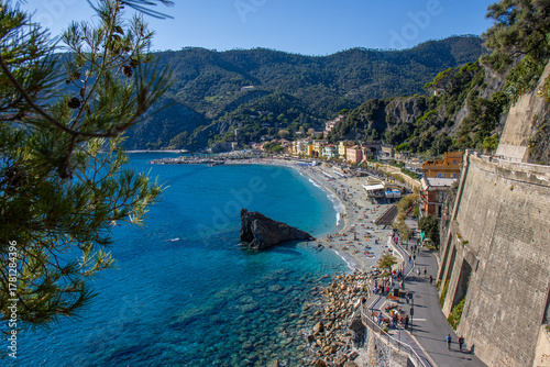 Fototapeta Naklejka Na Ścianę i Meble -  Monterosso al Mare beach seen from above, with its turquoise sea, rows of umbrellas, and colorful houses typical of the Ligurian coast. Sunny day with Mediterranean light. Cinque Terre, Italy
