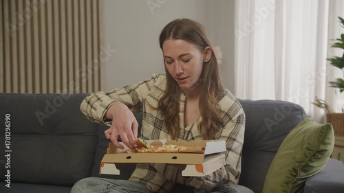 Woman Enjoying Pizza Slice While Relaxing At Home On Comfortable Couch