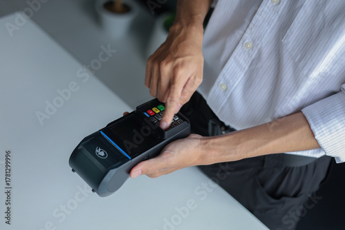 A person using a point-of-sale (POS) terminal, also known as a credit card machine, to process a transaction.