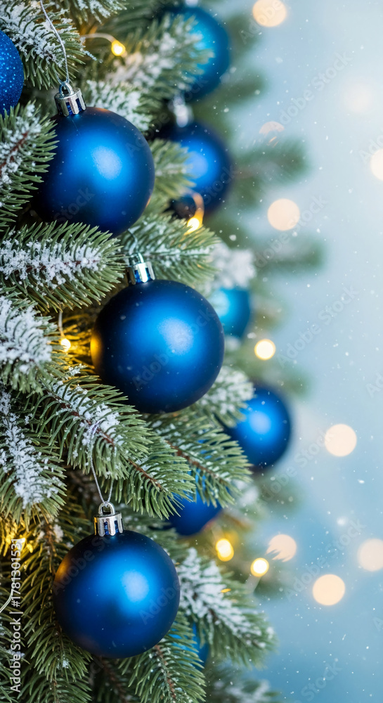 Fototapeta premium Close-up of green fir with snow, decorated with blue bauble and warm light, representing holiday, celebration, and joyous festive spirit