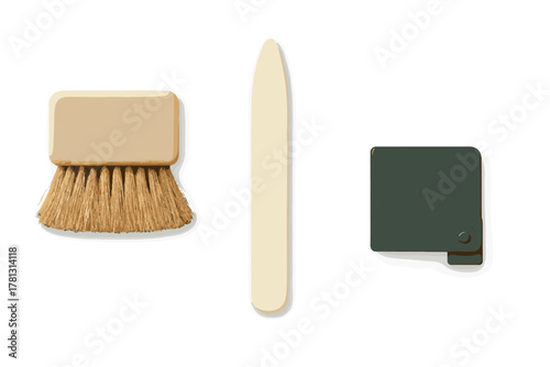 Minimalist arrangement of craft and stationery tools including a brush, bone folder, and small folding case