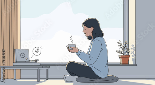 Young asian female sitting cross-legged indoors, peacefully drinking coffee and enjoying music from a record player by the window.