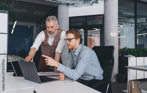 Φωτογραφία Businessmen review laptop data together in collaborative session