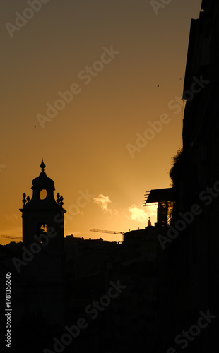 Church spire and cranes, all in sillhoette in Lisbon, Portugal