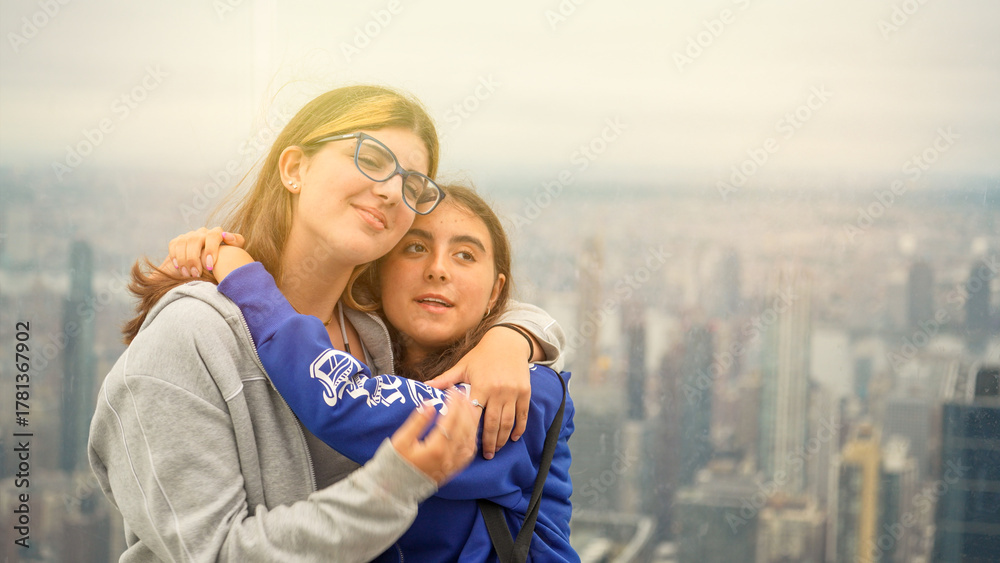 Fototapeta premium Friends embracing with Manhattan cityscape in the background captured from a high-rise building