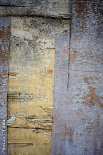 A wooden surface with a large tear in it. The tear is jagged and uneven, and the wood is chipped and worn. Scene is one of decay and neglect, as the wood has been damaged