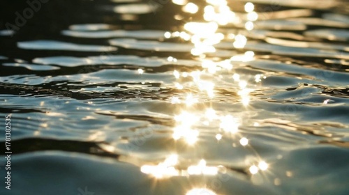 Golden sunlight sparkles on gentle water ripples creating a beautiful abstract pattern and serene