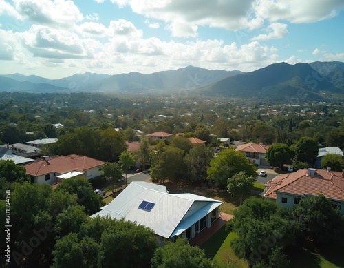 Wallpaper Mural Aerial view of suburb with houses and green trees under a cloudy blue sky. Mountains in the distance, sunny afternoon light illuminates residential area. Torontodigital.ca