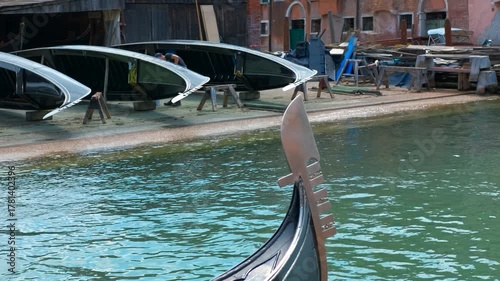Gondola ferro or prow detail floating on a venice canal. Close-up of a gondola's ferro, the decorative metal piece at the prow, reflecting in the calm canal water of venice, italy