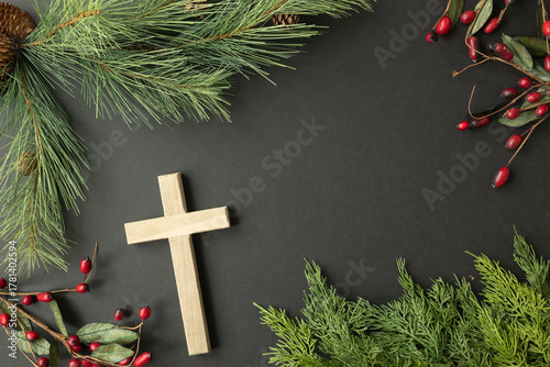 Cross, evergreen branches and red berries on a black background