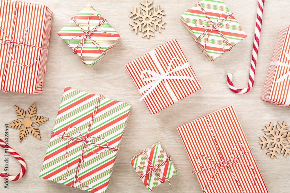 Obraz premium Many striped Christmas gift boxes on wooden background, top view
